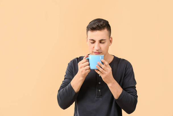Komea nuori mies kuppi teetä värillinen tausta - Valokuva, kuva