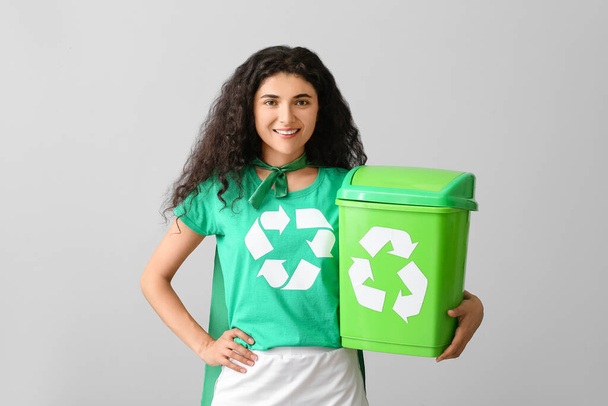 Mulher vestida de eco super-herói com lixo no fundo cinza
 - Foto, Imagem
