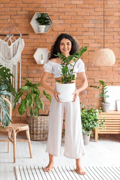 Beautiful young woman with houseplant at home. Ecology concept - Foto, immagini