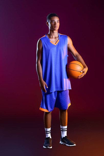 Joven jugador de baloncesto afroamericano sobre fondo oscuro
 - Foto, imagen