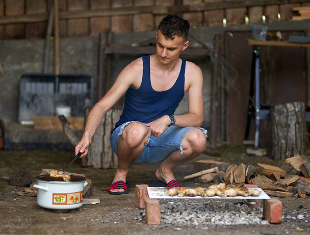 Young man grilling a variety of meat at the barbecue - Fotó, kép
