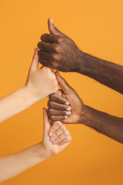 Hands of Caucasian woman and African-American man showing thumb-up gesture on color background. Racism concept - Photo, Image