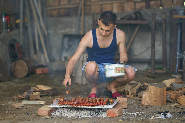 Young man grilling a variety of meat at the barbecue - Foto, imagen