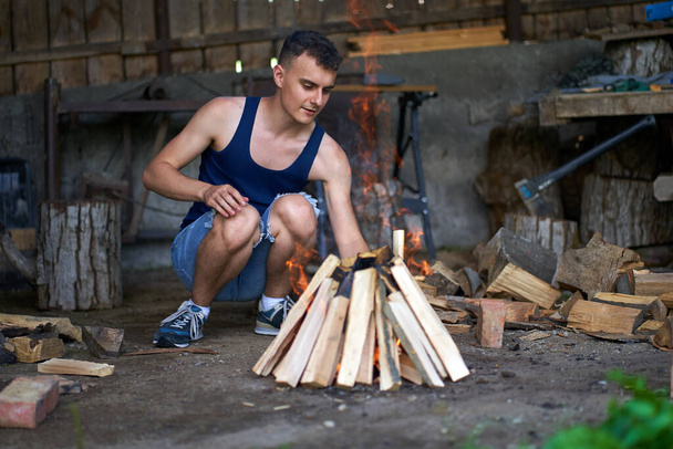 Young man preparing a fire for the barbecue - Fotó, kép