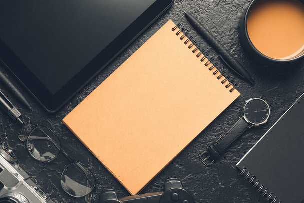 Cuaderno con taza de café y tableta sobre fondo oscuro
 - Foto, imagen