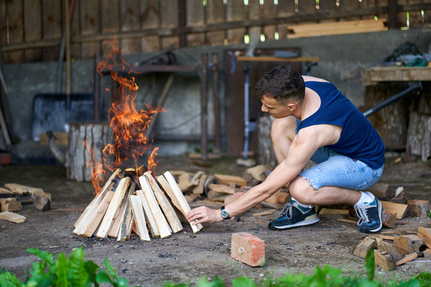 Young man preparing a fire for the barbecue - Fotó, kép