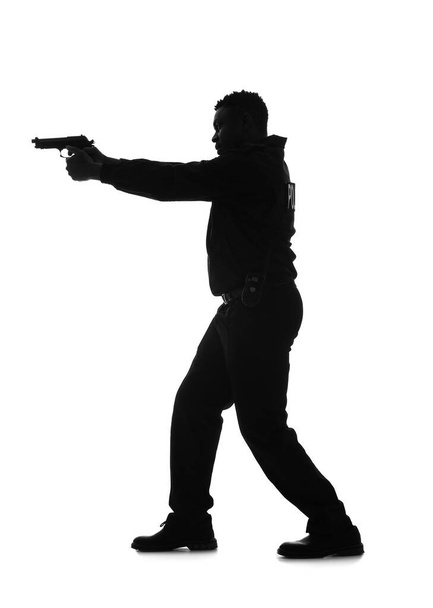 Silhouette of aggressive African-American police officer with gun on white background - Foto, Bild