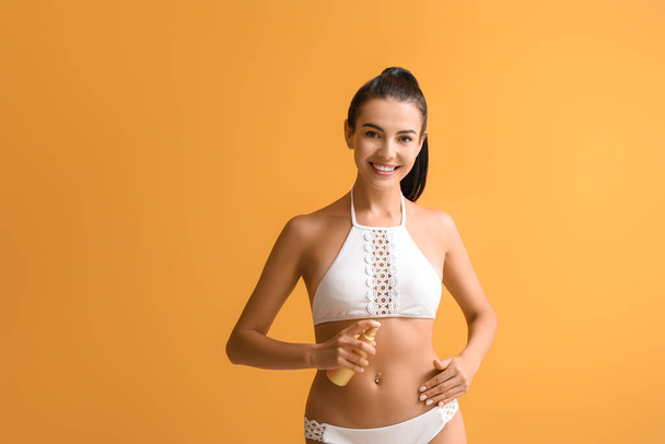 Happy young woman with sun protection cream on color background - Φωτογραφία, εικόνα