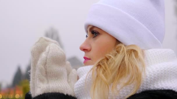 Chiudi donna congelato in cappello bianco, sciarpa, guanti riscalda le mani, palme sfregamento - Filmati, video