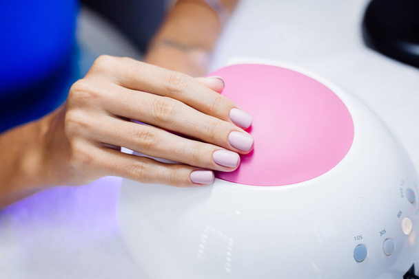 Hardware manicure proces. Mooie vrouwelijke handen. Vinger nagel behandeling, het maken van proces. Gel polish roze, paars. Schoonheids- en handzorgconcept. - Foto, afbeelding