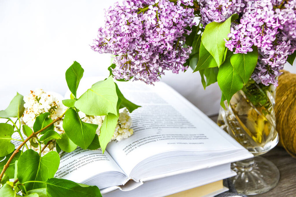 Lilac spring flower bouquet in glass vase on table with rope and books, copy space, holiday congratulation background - Photo, Image