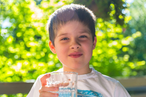 Un ragazzo che beve acqua in una calda giornata estiva - Foto, immagini