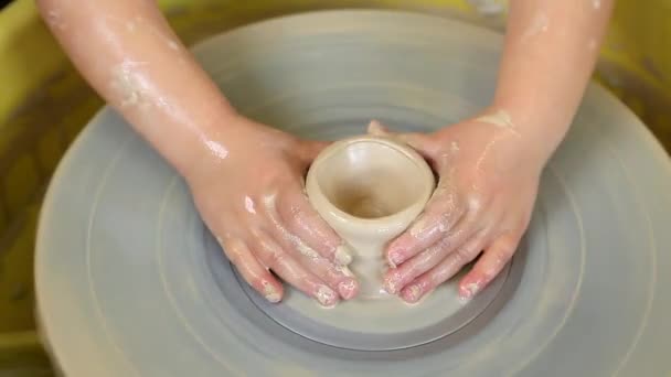 Le mani da bambini imparano a creare prodotti di argilla sulla ruota di un vasaio. Masterclass per bambini in laboratorio di ceramica. Arte, artigianato - Filmati, video