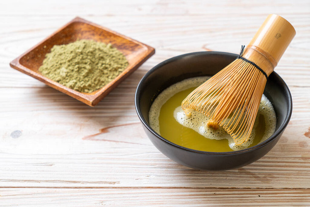 hot matcha green tea cup with green tea powder and bamboo whisk - Foto, afbeelding