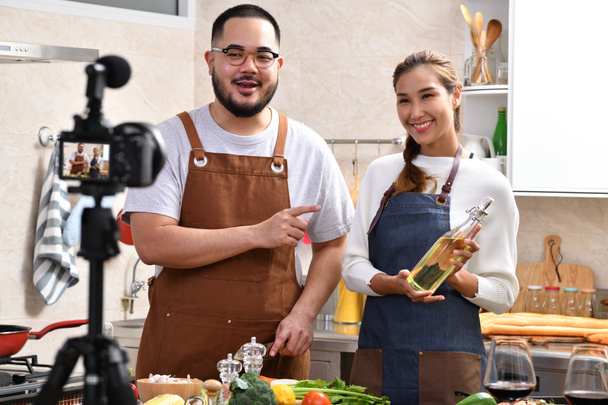 Joven pareja asiática bloguera vlogger e influencer online grabando contenido de video sobre comida saludable en la cocina
 - Foto, Imagen