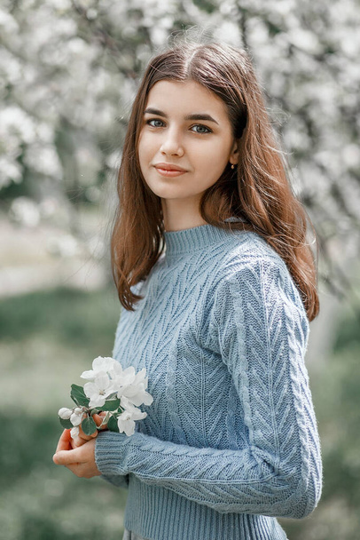 girl in a blooming garden in a blue jacket - Fotografie, Obrázek