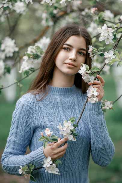 girl in a blooming garden in a blue jacket - Zdjęcie, obraz
