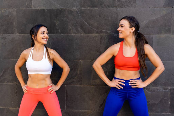 Two young Caucasian athletic female friends doing exercises and stretching outside - healthy lifestyle concept - Photo, image
