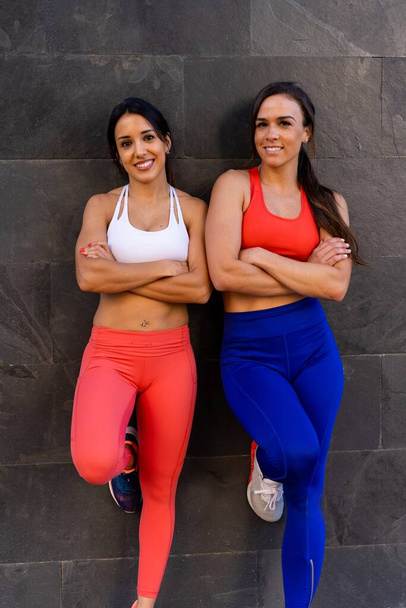 Two young Caucasian athletic female friends doing exercises and stretching outside - healthy lifestyle concept - Foto, afbeelding
