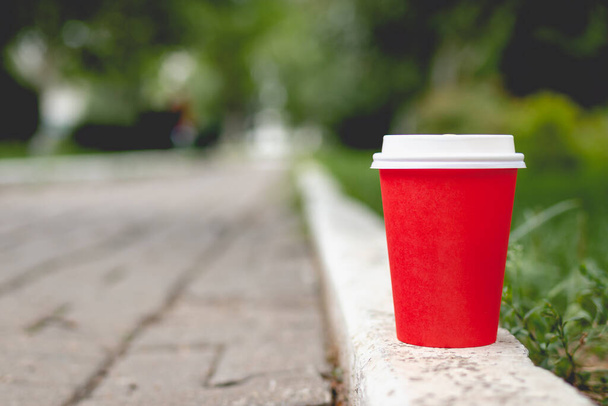 Red coffee paper cup mockup on nature background. Summer lifestyle shot. - Photo, Image