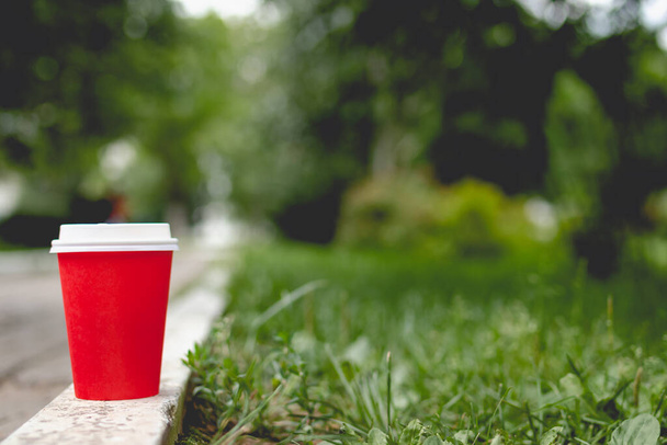 自然を背景にしたレッドコーヒーペーパーカップモックアップ。夏のライフスタイルショット. - 写真・画像