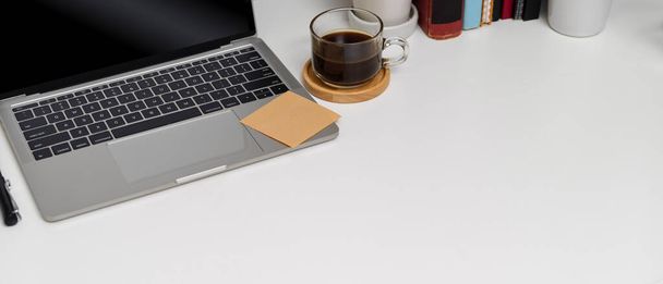 Cropped shot of modern worktable with copy space, coffee cup, stationery, books and decoration on white table - Photo, Image