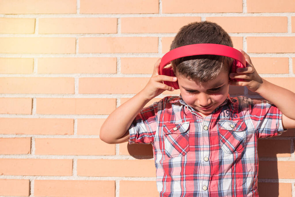 portrait kid listening to music with headphones on brick wall - Photo, Image