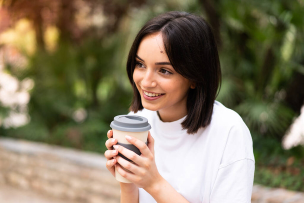 Joven mujer bonita sosteniendo café para llevar al aire libre - Foto, imagen