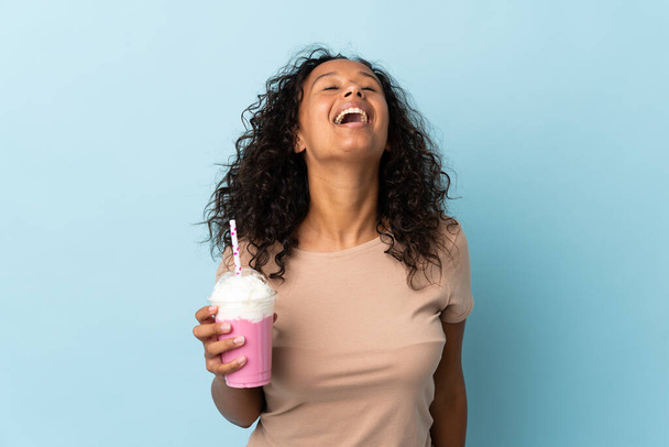 Teenager lány eper tejturmix elszigetelt kék háttér nevetés - Fotó, kép
