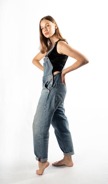 Jovem mulher atraente posando em macacão jeans
  - Foto, Imagem