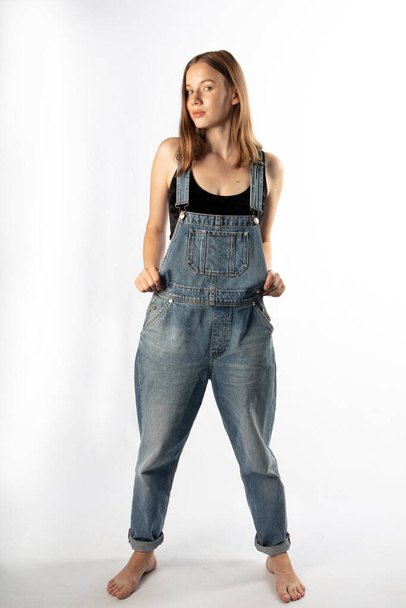 Young attractive woman posing in denim overalls  - Фото, зображення