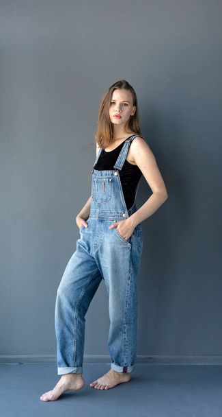 Young attractive woman posing in denim overalls  - 写真・画像