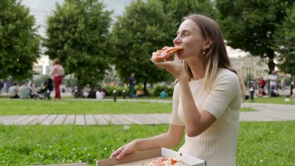 Mujer comiendo pizza al aire libre en un parque
 - Metraje, vídeo