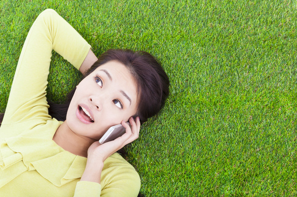 улыбающаяся молодая женщина слушает с мобильного телефона на лугу
 - Фото, изображение