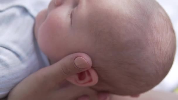 Τα χέρια των μητέρων κρατούν το κεφάλι του νεογέννητου μωρού σε μια βόλτα. - Πλάνα, βίντεο
