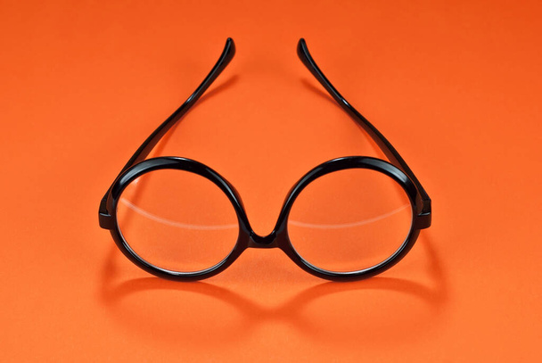 Různé typy brýlí na oranžovém pozadí zblízka. Brýle s kulatými rámy.  - Fotografie, Obrázek