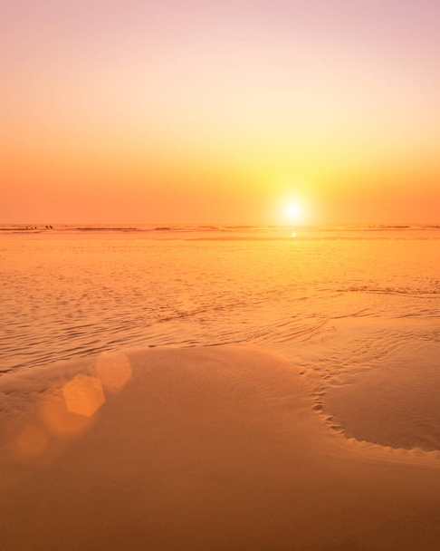 Un coucher de soleil coloré ou lever de soleil sur le bord de la mer avec une plage de sable avec des impuretés de cendres volcaniques. Mandrem, Goa, Inde. Beau paysage marin. - Photo, image