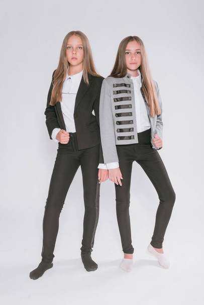 Two cute girls schoolgirls in a trendy school uniform on a white background. School fashion. Children's school fashion clothes - Photo, Image