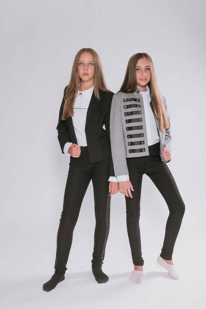 Two cute girls schoolgirls in a trendy school uniform on a white background. School fashion. Children's school fashion clothes - Foto, Bild