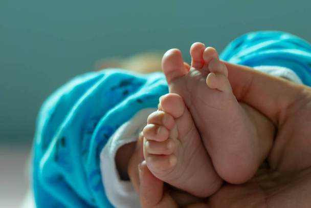 Αφηρημένη θολή εικόνα των νεογέννητων ποδιών του μωρού στα χέρια των γονέων - Φωτογραφία, εικόνα