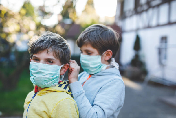 Twee jongens met een medisch masker als bescherming tegen een pandemische coronavirusziekte. Kinderen, lieve broers en zussen en beste vrienden die beschermende uitrusting gebruiken als strijd tegen covid 19. - Foto, afbeelding