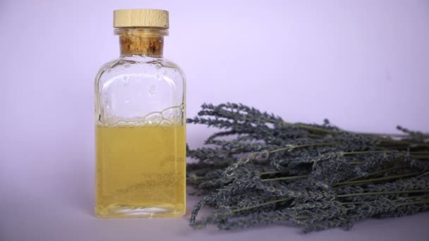 Levandulový esenciální olej, láhev a levandulová kytice na fialovém pozadí - Záběry, video