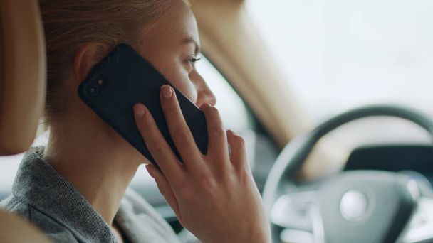 Back view of woman using phone behind steering wheel. Girl calling smartphone - Photo, image