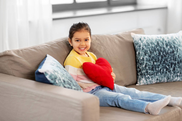 happy little girl with heart shaped pillow at home - Valokuva, kuva