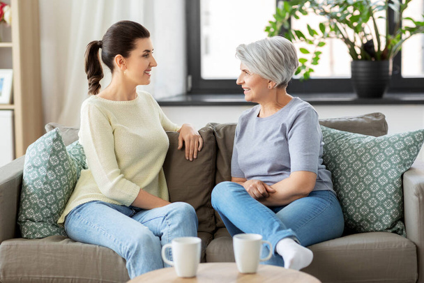 senior mother with adult daughter talking at home - Foto, imagen