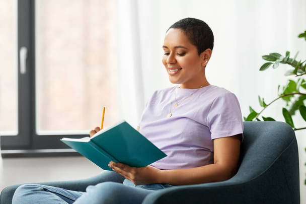 happy african american woman with diary at home - Photo, image