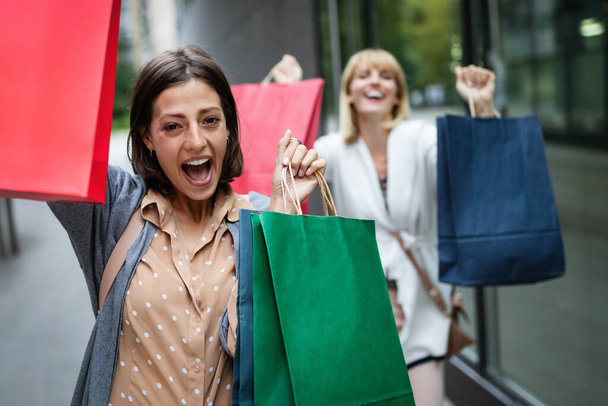 Beautiful young women with shopping bags having fun on city street - Фото, зображення
