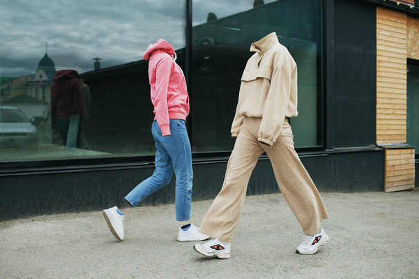 Prázdné ženské oblečení chodí po ulici v mikinách, džínách, teniskách a barevných trenérech. - Fotografie, Obrázek