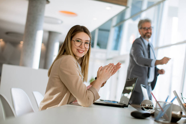 Mooie jonge vrouw klappen handen na succesvolle zakelijke ontmoeting in het moderne kantoor - Foto, afbeelding