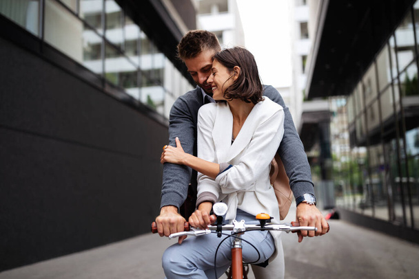 Portrait of happy young couple in love riding a bicycle and having fun together outdoor - Photo, image